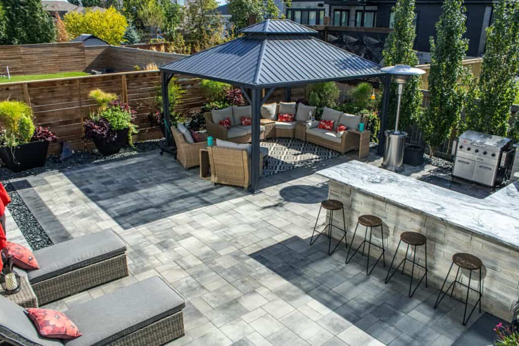 Custom hardscaping design with stone patio, outdoor seating area, and modern backyard landscaping.
