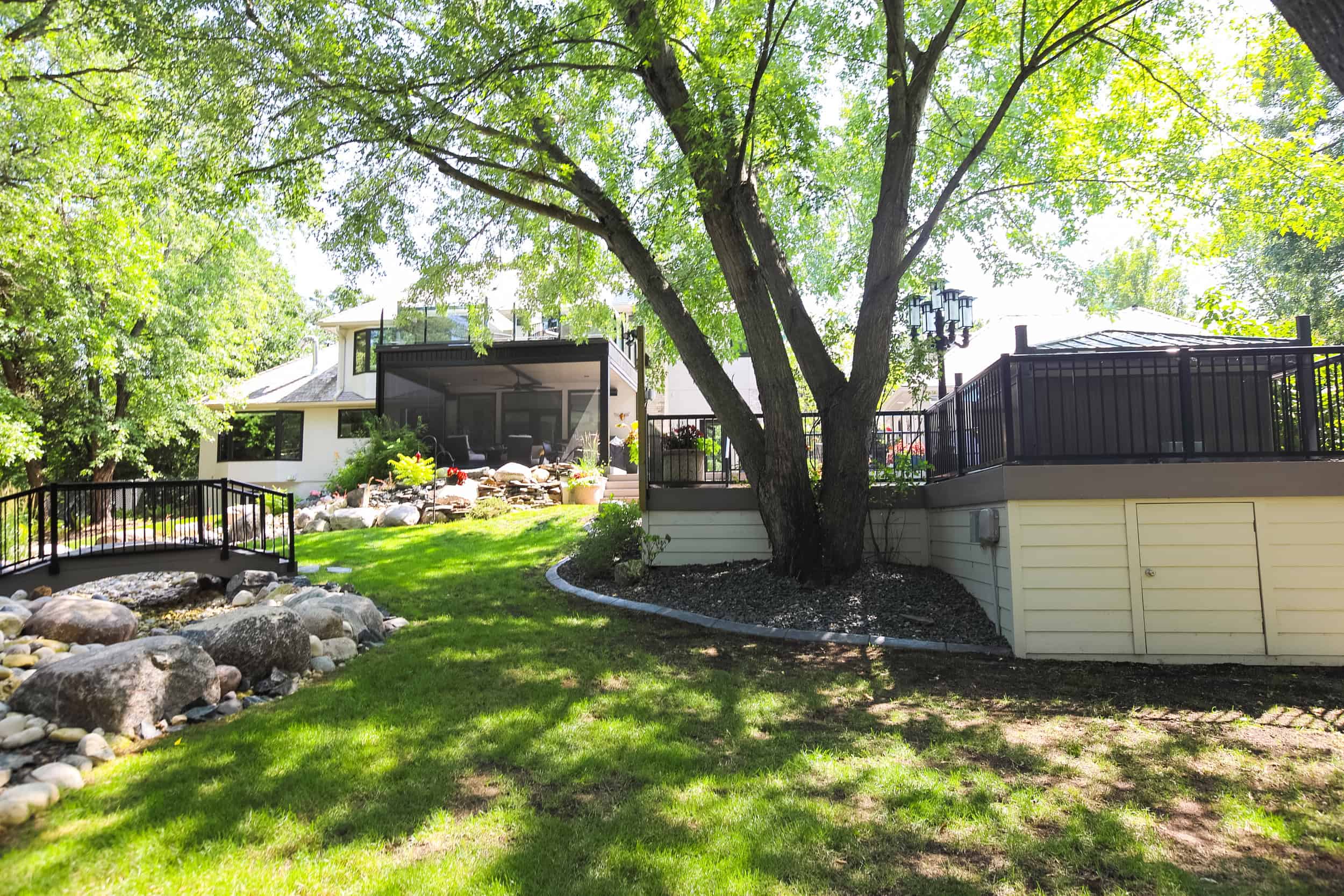 Lawn maintenance and landscaping services by Lawn N Order showcasing a lush green backyard with manicured grass, rock features, and a well-designed outdoor space in a residential setting.