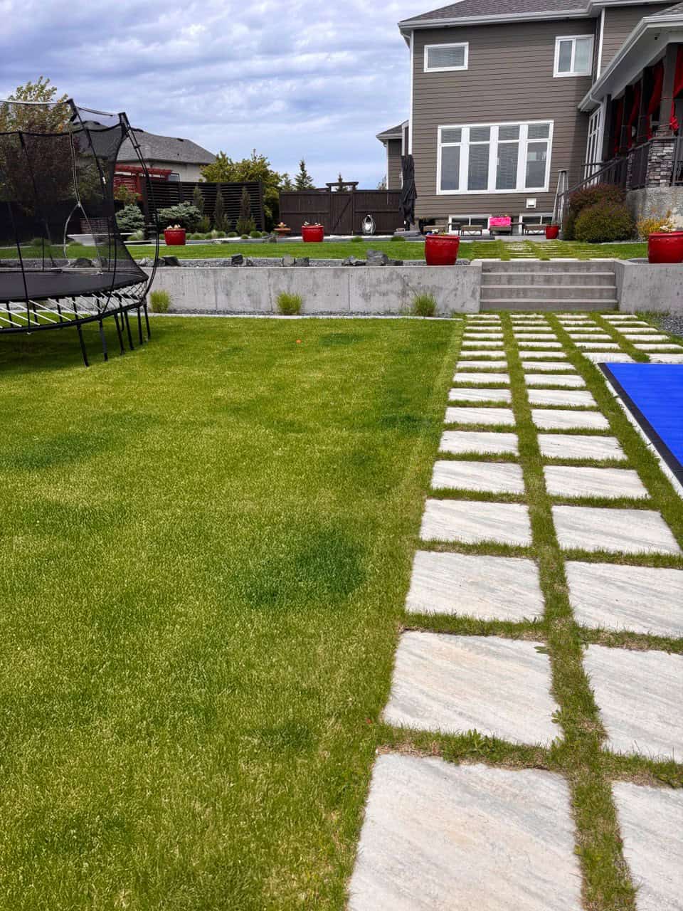 Front yard in Deerpoint featuring square stepping stones and artificial turf lawn