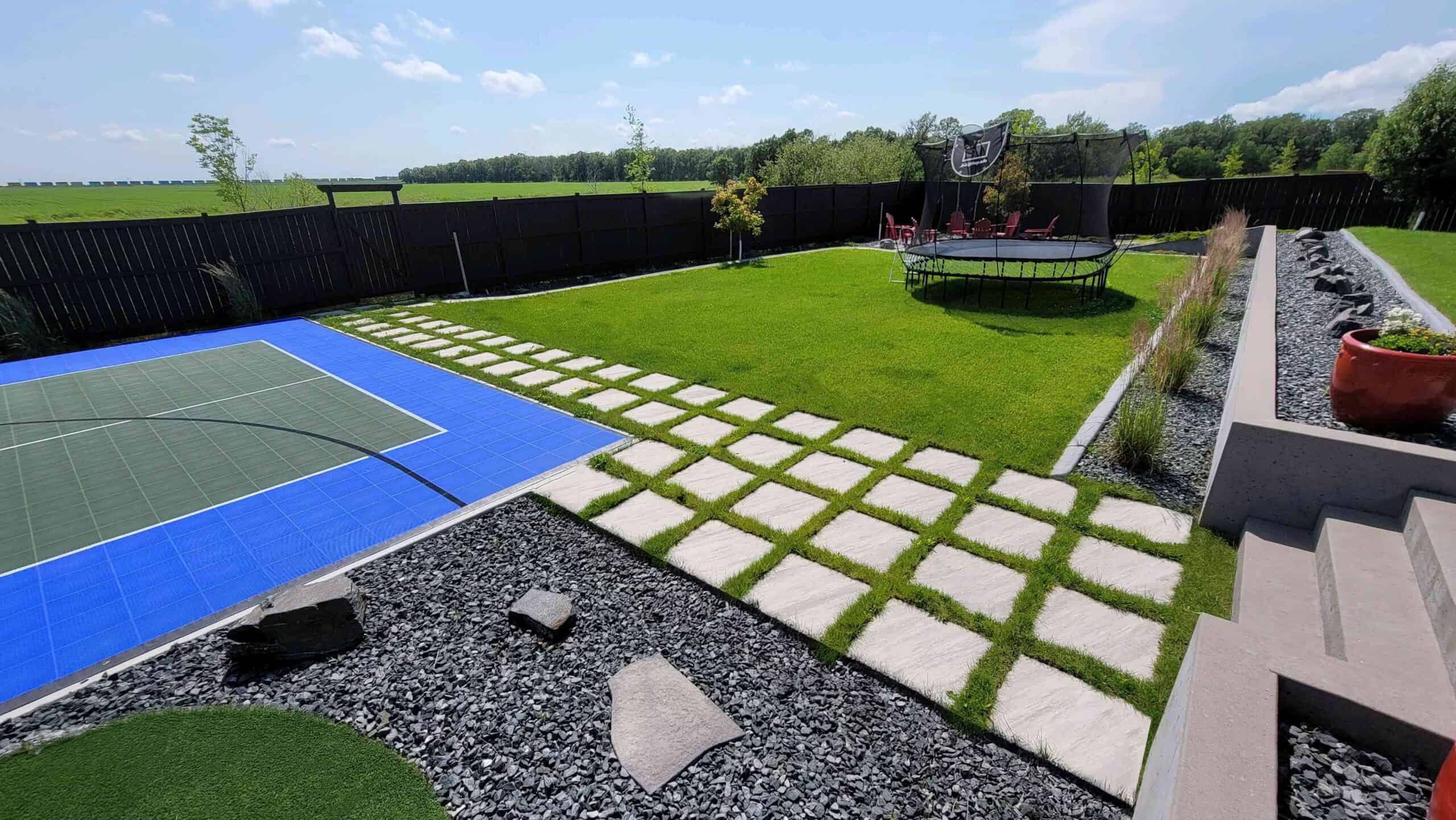 Outdoor design with grid paver walkway and synthetic turf lawn in Deerpoint yard