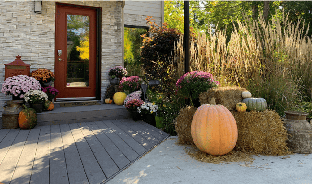 Front entry decorated with large pumpkin, mums, and hay bales for fall curb appeal