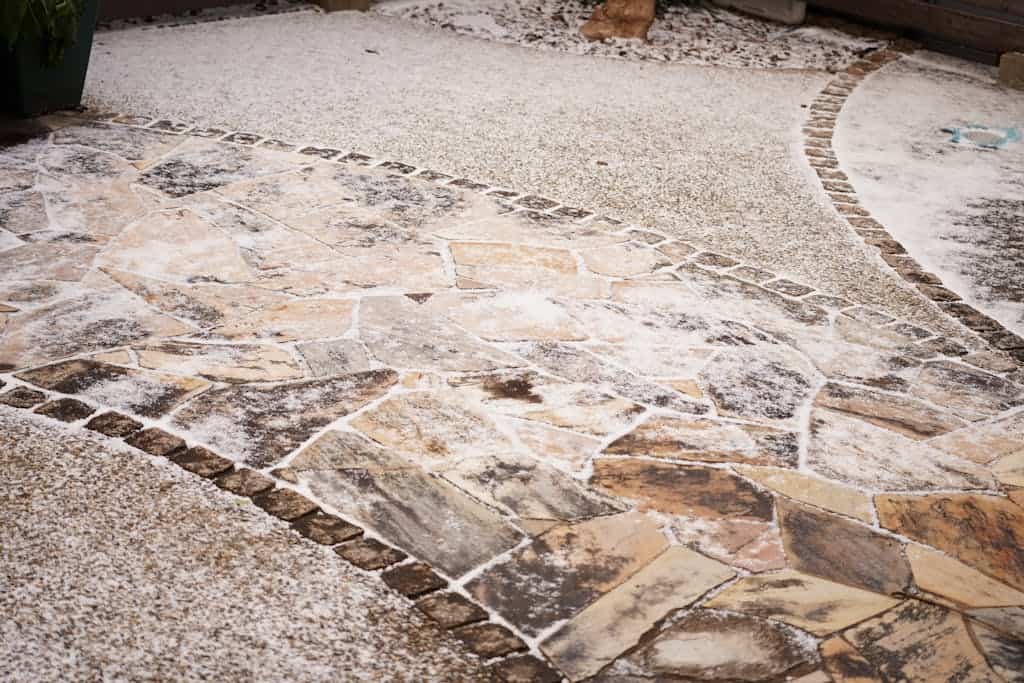 Artistic snow-dusted stone patio with intricate patterns and textures, showcasing winter charm.